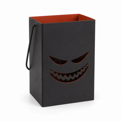 Black Halloween metal lantern bag with a spooky face cutout and orange-red interior for seasonal candle decor.