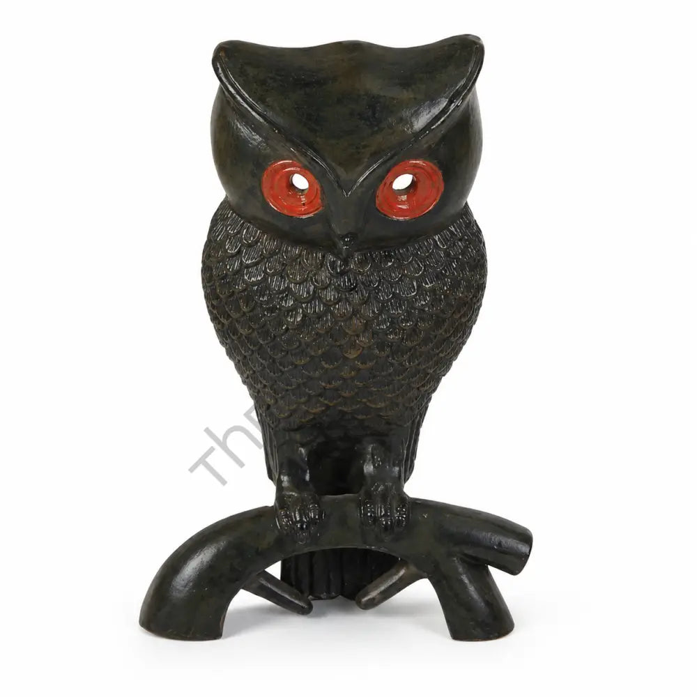 Striking black owl figurine with red eyes perched on a branch for home office decor.