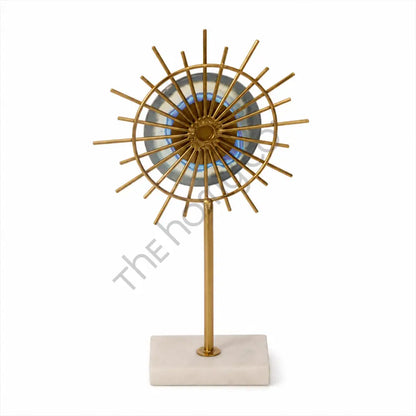 Gold sunburst sculpture with a blue accent center on a marble base for modern home decor.