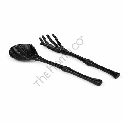 Black skeleton hand spoon and fork serving set with bone-inspired handles for Halloween party table decor.