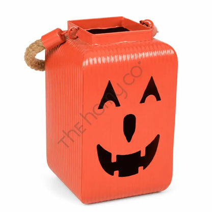 Orange pumpkin metal lantern with a jack-o-lantern face and rustic rope handles for Halloween decor.